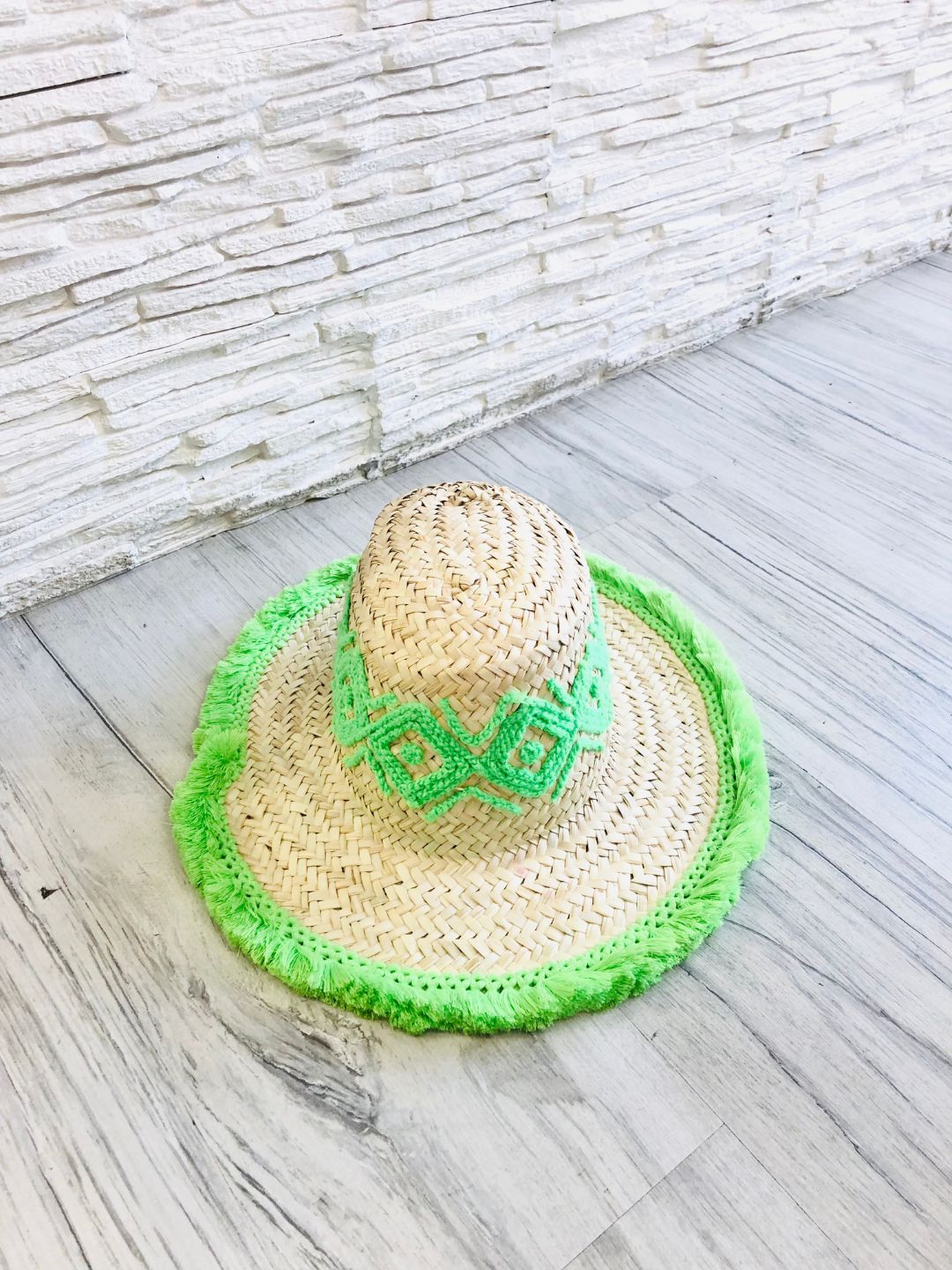Cappello realizzato con grosse trecce di paglia, ricamato intorno al cappello e rifinito sul bordo con delle piccole frange.