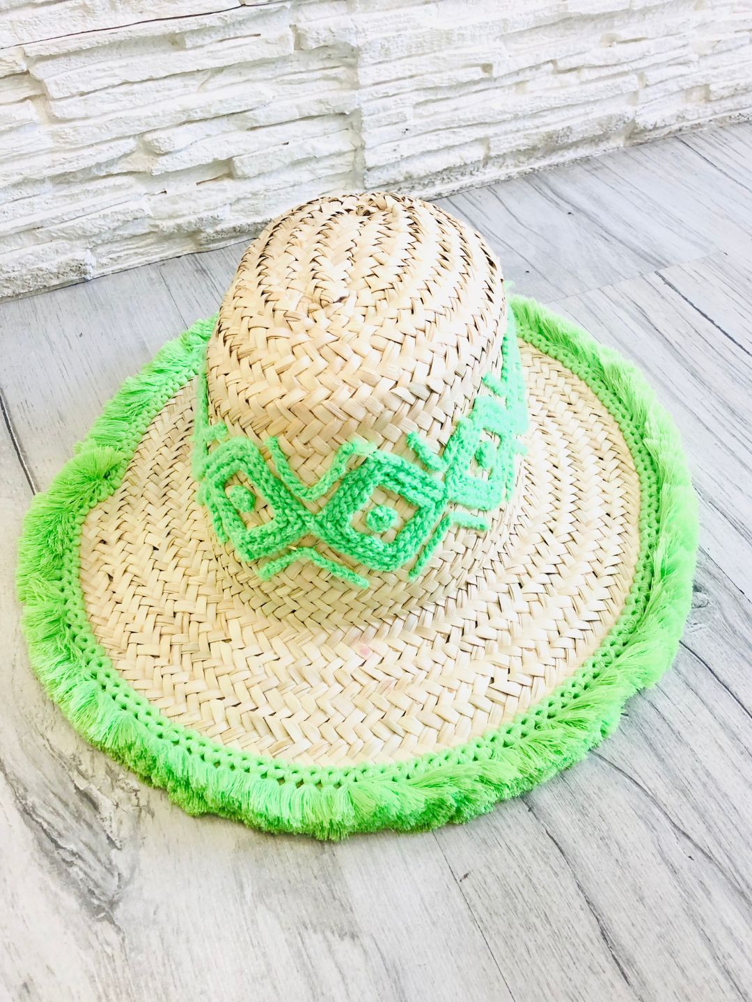 Cappello realizzato con grosse trecce di paglia, ricamato intorno al cappello e rifinito sul bordo con delle piccole frange.